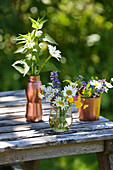 Wildflower posies in glass vase and copper-coloured containers