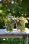 Wildflower posies in glass vases decorated with paint pens