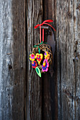 Small willow wreath decorated with colourful felt flowers and felt hearts
