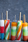 Various colourful striped popsicles on a blue countertop with a blue background