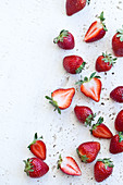 Strawberries, whole and halved, photographed from above on a white textured surface