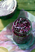 Glass jar full of tasty fermented red cabbage placed on wooden table
