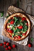 Delicious pizza with tomato and salad placed with checkered towel on wooden background
