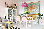 White table, bench and pink chairs below map decorating wall in dining area