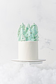 A white Christmas cake decorated with a meringue tree