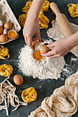 Close view of woman hands making dough for pasta on stone table