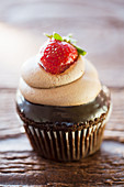 Chocolate cupcake with chocolate cream and strawberry on the top