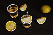 Two traditional tequila shots served with pieces of fresh lime and salt