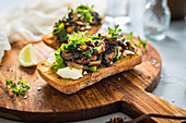Roasted ciabatta with bryndza, mushroom and kale on a wooden board
