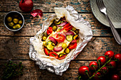 Feta with tomatoes, zucchini, olives, onions and thyme in parchment paper