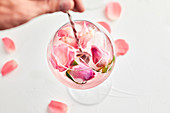 Stirring the gin and tonic cocktail with rose infused tonic