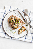 A slice of bread topped with mushrooms on a plate with silver cutlery