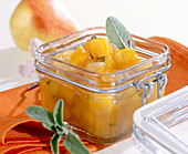 Homemade pumpkin and pear chutney in a jar with fresh sage