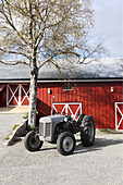 Traktor vor einer Birke und einer roten Scheune