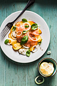 Caprese salad with nectarines, basil, mozzarella cheese and smoked salmon, spiced with black pepper, salt and olive oil