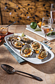Smoked and Grilled Oysters on oblong with serving plate with rose in wine glass pairing