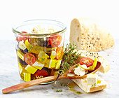Feta cheese preserved in olive oil with tomatoes, garlic, jalapenos and olives served with unleavened sesame seed bread