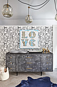 Nursery with rabbit wallpaper and 'Love' motto on wall above grey dresser