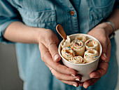 Vanilla rolled ice cream in cone cup in woman hands
