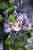 Doll's face surrounded by purple lilac