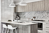 Modern kitchen in shades of grey and white with breakfast bar on island counter