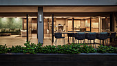 Langer Tisch mit Designer-Outdoor- Sesseln auf der Terrasse, Blick in offenen Wohnraum mit Küche und Lounge