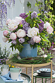 Fragrance bouquet of peonies and lilac in a wreath of grasses and branches