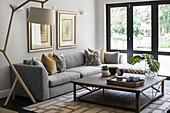 Grey corner sofa, standard lamp and coffee table in front of terrace doors