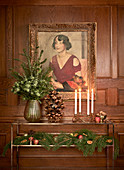 Festively decorated console table below painting on wooden wall panelling