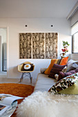 Scatter cushions on sofa and classic chair below triptych artwork in modern interior