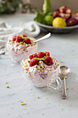 Eton Mess with raspberries and pistachio nuts served in glass cups