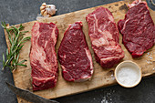 Various raw Black Angus steaks on a wooden board