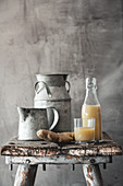 A ginger shot in a glass and a bottle on a rustic wooden stool