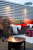 Bench with cushions under lights and fire bowl on terrace