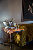 Gefüllte Champagnergläser auf elegantem Beistelltisch neben senfgelber Couch