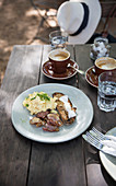 Scrambled eggs with bacon and toasted bread, with espresso on a table in the open air