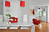 Modern dining room in open-plan interior with red accents