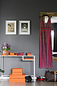 Dress hanging on mirror next to console table and orange boxes