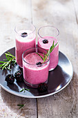 Blackberry drinking yoghurt in glasses with fresh rosemary