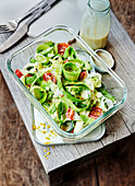 Zoodles with cherry tomatoes, spring onions and yoghurt mustard sauce in a to-go box