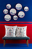 Cushions on bench below decorative wall plates on blue-and-red wall