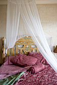 Claret bed linen on bed with canopy