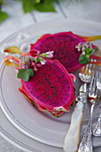 Halved dragon fruit with elegant silver cutlery on a plate