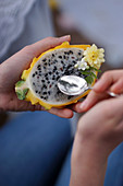 A person spooning pulp from a yellow dragon fruit