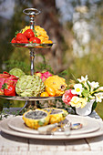 Etagere mit Erdbeeren und exotischen Früchten auf Tisch im Freien