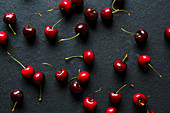 From above bright red appetizing cherries with stems on black background
