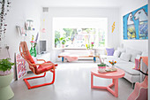 White, light-flooded living room with bright accents of colour