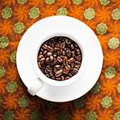 Kaffeebohnen in Kaffeetasse auf Stoffuntergrund