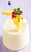 Coconut and pineapple smoothie with yoghurt and a fruit skewer