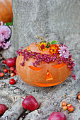 Carved pumpkin, wreath of pepper and shrub verbenas